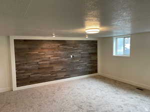 Interior space with a textured ceiling, carpet floors, and wooden walls