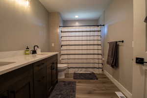 Bathroom with wood-type flooring, toilet, walk in shower, and vanity