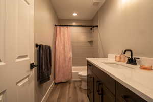 Full bathroom with vanity, toilet, hardwood / wood-style flooring, and shower / bath combo with shower curtain