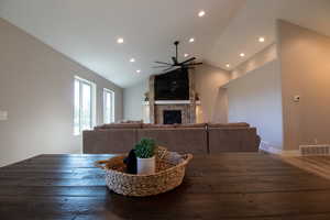 Dining space with a fireplace, dark hardwood / wood-style flooring, high vaulted ceiling, and ceiling fan