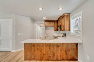 Kitchen with light wood-type flooring, stainless steel appliances, kitchen peninsula, and sink