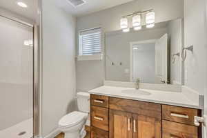 Bathroom with vanity, toilet, and a shower with shower door