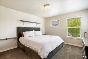 Bedroom with a textured ceiling and dark carpet