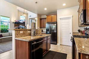 Kitchen featuring hanging light fixtures, stainless steel appliances, sink, and a kitchen island with sink