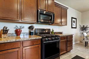 Kitchen featuring light tile patterned floors, light stone countertops, and range with gas cooktop