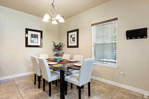 Dining space featuring light tile patterned flooring, a notable chandelier, and a healthy amount of sunlight