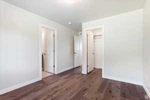 Unfurnished bedroom with a closet, a walk in closet, and dark hardwood / wood-style floors