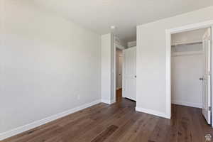 Unfurnished bedroom with dark wood-type flooring and a closet