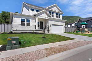 View of front of house featuring a mountain view, a garage, a playground, and a front yard