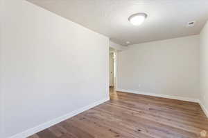 Spare room with hardwood / wood-style floors and a textured ceiling