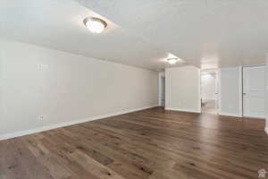 Basement featuring a textured ceiling and dark hardwood / wood-style floors