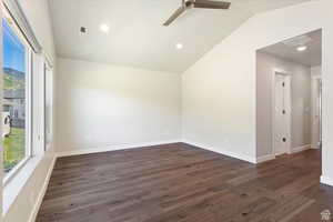 Unfurnished room with ceiling fan, dark hardwood / wood-style flooring, and vaulted ceiling