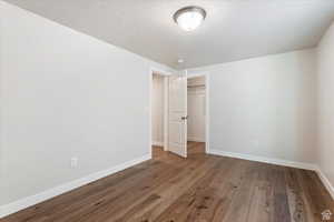 Unfurnished bedroom featuring a textured ceiling, hardwood / wood-style floors, and a closet