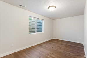 Empty room featuring wood-type flooring and a textured ceiling