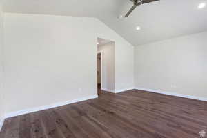 Unfurnished room with dark wood-type flooring, ceiling fan, and vaulted ceiling