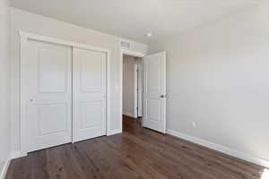 Unfurnished bedroom featuring dark wood-type flooring and a closet