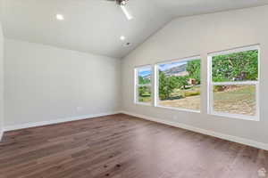 Spare room featuring lofted ceiling, wood-type flooring, and ceiling fan