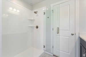 Bathroom featuring a shower with door, vanity, and tile patterned floors