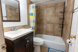 Full bathroom with tile patterned flooring, shower / bath combo, toilet, vanity, and a textured ceiling