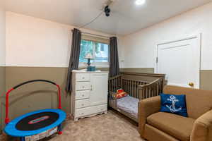 Bedroom featuring light carpet and a crib