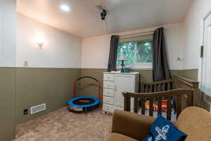 Carpeted bedroom featuring a nursery area