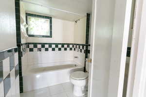 Bathroom with tile walls, tile patterned flooring, and toilet