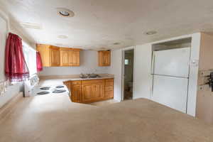 Kitchen featuring white appliances, a textured ceiling, and sink