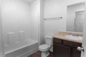 Full bathroom with hardwood / wood-style floors, toilet, bathtub / shower combination, and vanity