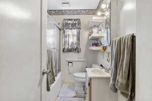 Full bathroom featuring tile patterned floors, toilet, combined bath / shower with glass door, and vanity