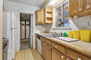 Kitchen with dishwasher, stainless steel stove, sink, and backsplash