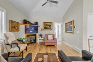 Living room with ceiling fan, vaulted ceiling, and light hardwood / wood-style flooring