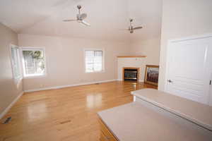 Unfurnished living room featuring lofted ceiling, ceiling fan, and light hardwood / wood-style flooring