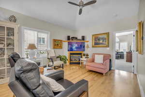 Living room with lofted ceiling, ceiling fan, and light wood-type flooring