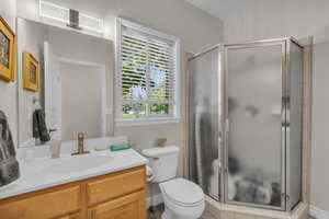 Bathroom featuring toilet, a shower with door, and vanity