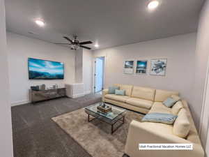 Living room featuring a textured ceiling, ceiling fan, and carpet