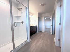 Bathroom featuring a textured ceiling, vanity, hardwood / wood-style flooring, and walk in shower