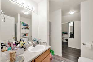 Bathroom featuring an enclosed shower, hardwood / wood-style floors, toilet, vanity, and a textured ceiling