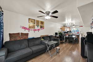 Living room with hardwood / wood-style floors and ceiling fan with notable chandelier