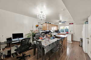 Dining area featuring a textured ceiling, sink, ceiling fan with notable chandelier, and light wood-type flooring