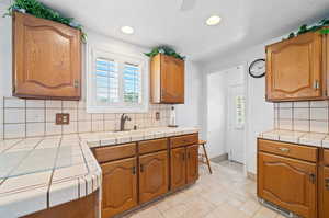 Kitchen featuring tile counters, a textured ceiling, tasteful backsplash, and sink