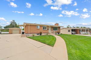 Ranch-style house with a garage, a front lawn, and an outdoor structure