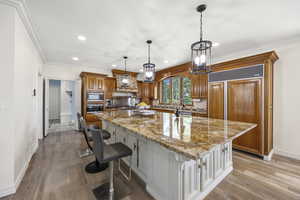 Kitchen with light wood-type flooring, a kitchen breakfast bar, and a large island