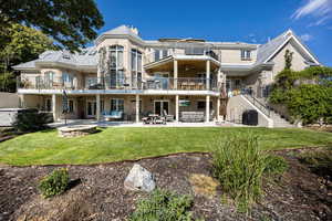 Rear view of house with a balcony, a yard, and a patio