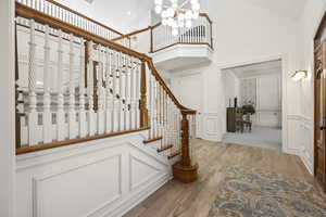 Stairs featuring a high ceiling, hardwood / wood-style floors, a chandelier, and ornamental molding