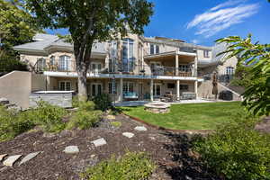 Rear view of house with a balcony, an outdoor fire pit, a yard, and a patio area