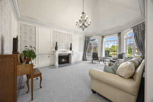 Living room featuring ornamental molding, a high end fireplace, light carpet, and an inviting chandelier