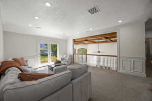 Carpeted living room with a textured ceiling, ceiling fan, and ornamental molding