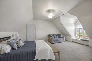 Bedroom with ceiling fan, a textured ceiling, light carpet, and vaulted ceiling