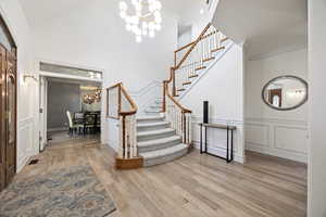 Foyer with light wood-type flooring, a notable chandelier, and ornamental molding