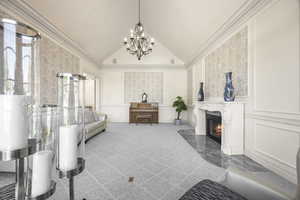 Interior space featuring an inviting chandelier, crown molding, vaulted ceiling, light colored carpet, and a premium fireplace